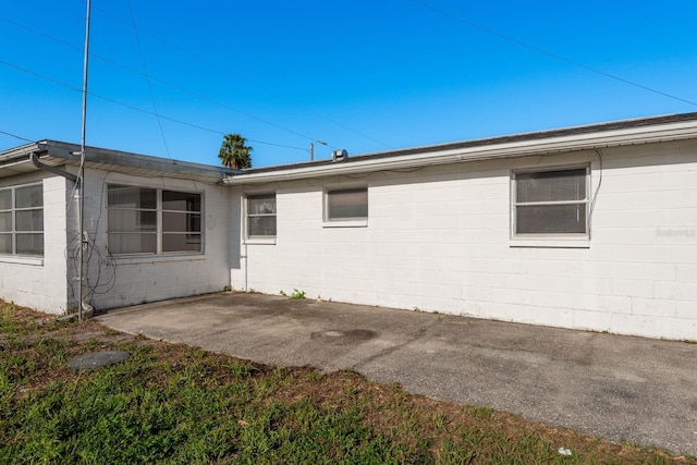 view of home's exterior with concrete block siding and a patio area