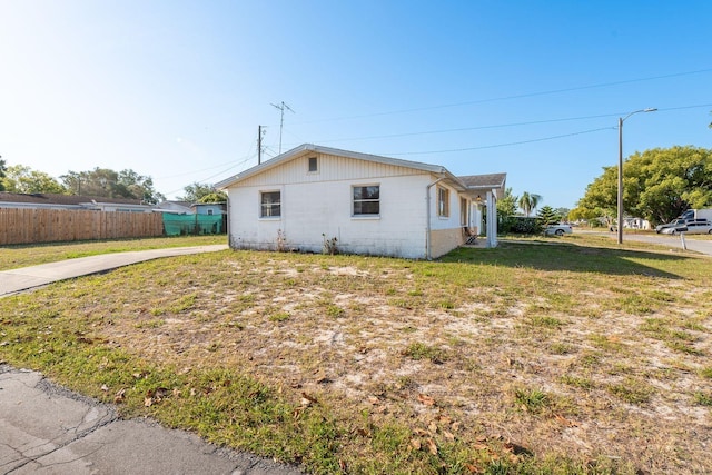 view of side of property featuring a lawn, fence, and concrete block siding