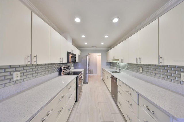 kitchen featuring stainless steel appliances, a sink, crown molding, tasteful backsplash, and white cabinetry