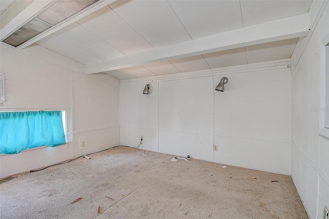 empty room with carpet floors, beamed ceiling, and visible vents