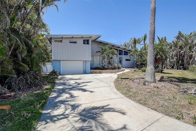 view of front of home with an attached garage, concrete driveway, and a balcony