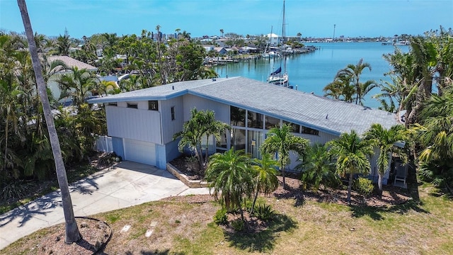 exterior space featuring a water view, an attached garage, driveway, and roof with shingles