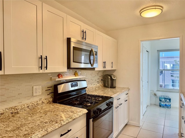 5501 80th St N Unit 509, Saint Petersburg, FL 33709 - kitchen with stainless steel appliances, tasteful backsplash, white cabinetry, and light stone counters