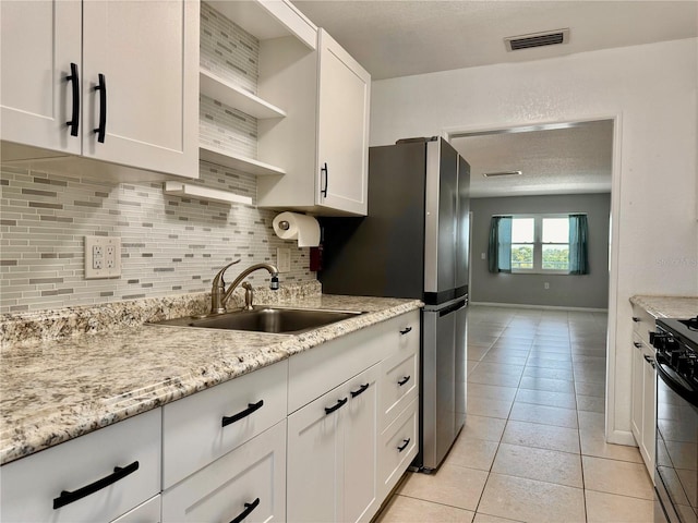 5501 80th St N Unit 509, Saint Petersburg, FL 33709 - kitchen with open shelves, backsplash, gas stove, white cabinetry, and light tile patterned floors