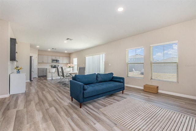 1646 Seth Dr, Winter Haven, FL 33880 - living area featuring light wood-type flooring, visible vents, baseboards, and a healthy amount of sunlight