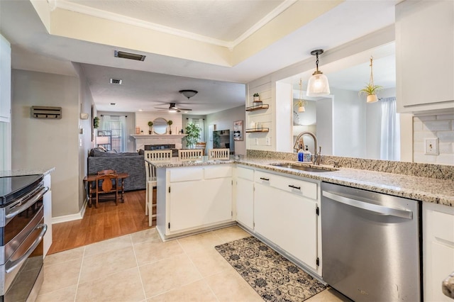 34 Hickory Ln, Safety Harbor, FL 34695 - kitchen with stainless steel appliances, a sink, open floor plan, a ceiling fan, and a fireplace