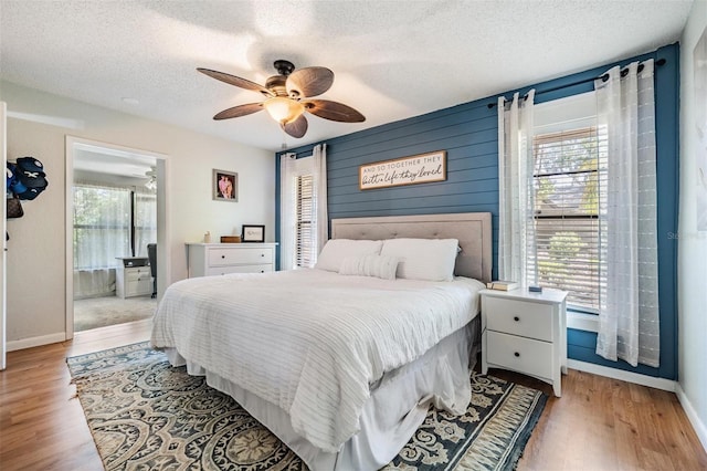34 Hickory Ln, Safety Harbor, FL 34695 - bedroom featuring a textured ceiling, connected bathroom, ceiling fan, light wood-style flooring, and baseboards