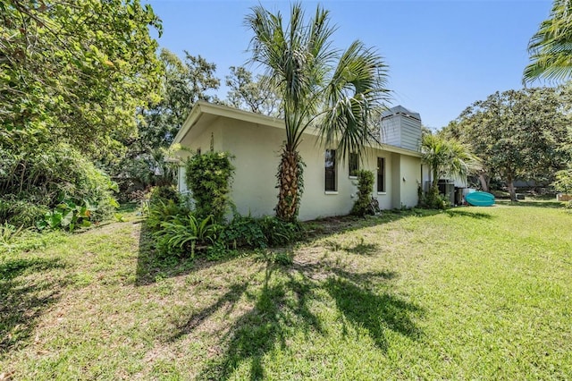 34 Hickory Ln, Safety Harbor, FL 34695 - view of side of home with stucco siding, a chimney, and a yard