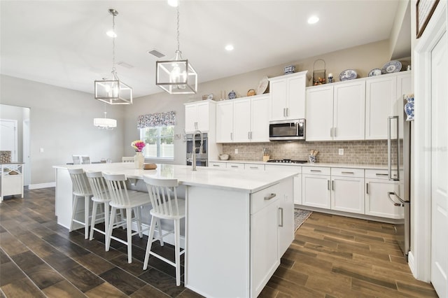 11852 Lake Lucaya Dr, Riverview, FL 33579 - kitchen featuring white cabinets, a kitchen island with sink, light countertops, stainless steel appliances, and backsplash