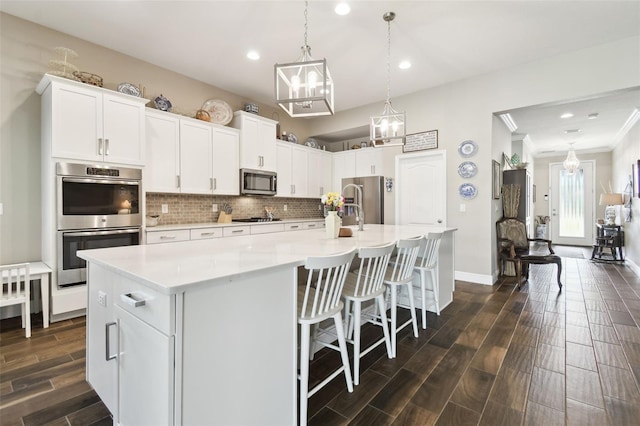 11852 Lake Lucaya Dr, Riverview, FL 33579 - kitchen featuring backsplash, a center island with sink, light countertops, white cabinets, and stainless steel appliances