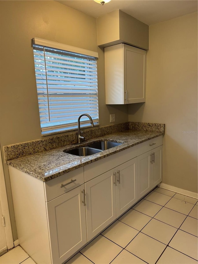 766 Beltrees St, Dunedin, FL 34698 - kitchen featuring a sink, light tile patterned floors, white cabinets, baseboards, and dark stone countertops