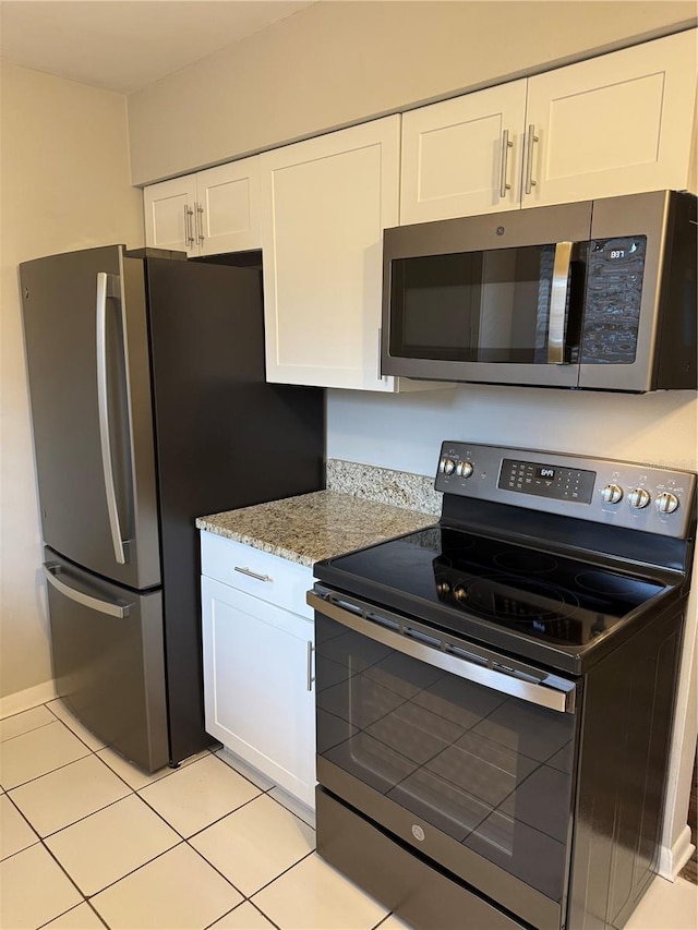 766 Beltrees St, Dunedin, FL 34698 - kitchen with appliances with stainless steel finishes, white cabinets, light tile patterned floors, and light stone counters