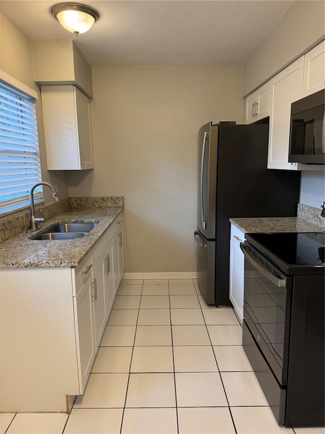 766 Beltrees St, Dunedin, FL 34698 - kitchen featuring black appliances, a sink, white cabinets, light tile patterned floors, and light stone counters