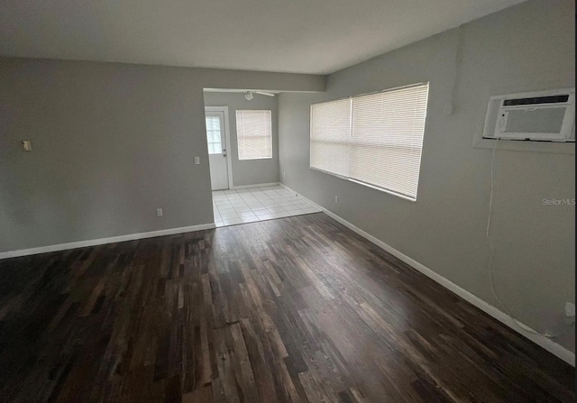 766 Beltrees St, Dunedin, FL 34698 - unfurnished room with an AC wall unit, wood finished floors, and baseboards