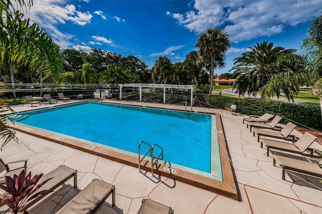community pool with fence and a patio area