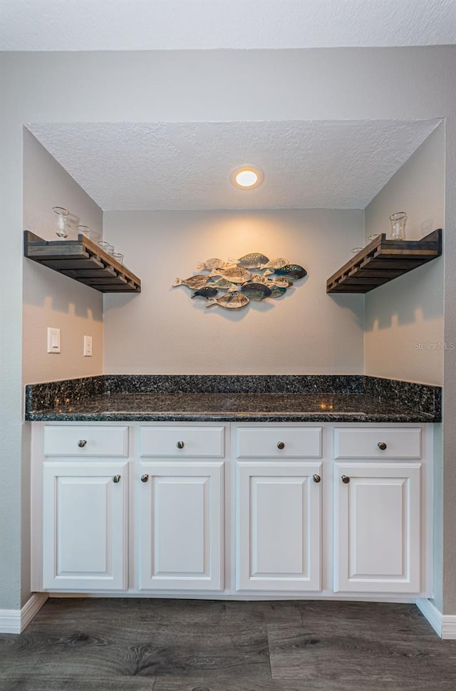 kitchen featuring white cabinets, dark wood finished floors, a textured ceiling, and baseboards