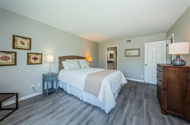 bedroom with dark wood finished floors, baseboards, and visible vents
