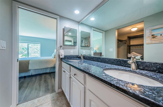 ensuite bathroom featuring a spacious closet, a sink, double vanity, and connected bathroom