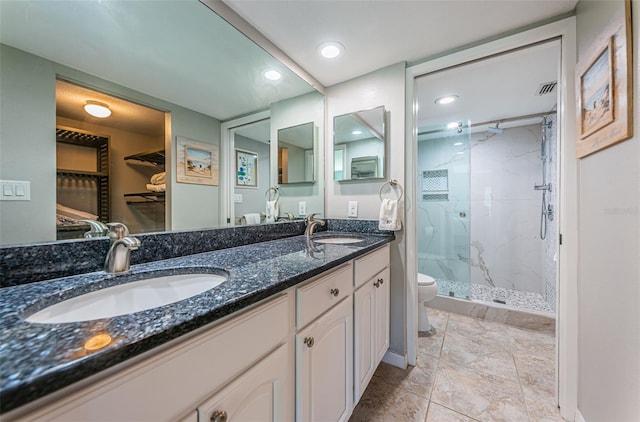 bathroom with double vanity, toilet, a marble finish shower, and a sink
