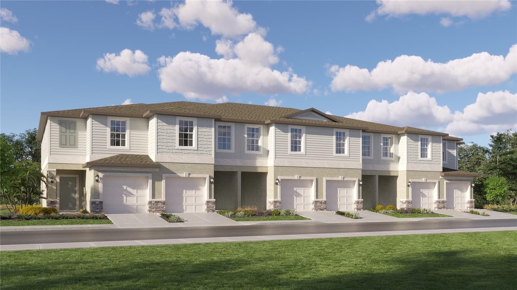 view of property with an attached garage and a front lawn