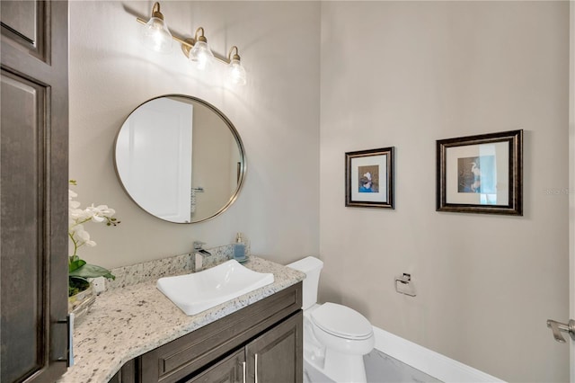 half bath featuring vanity, baseboards, toilet, and marble finish floor