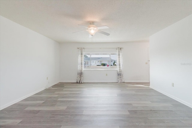 empty room with baseboards, a ceiling fan, a textured ceiling, and wood finished floors