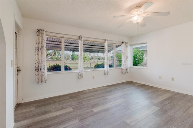 spare room featuring baseboards, a ceiling fan, a textured ceiling, and wood finished floors