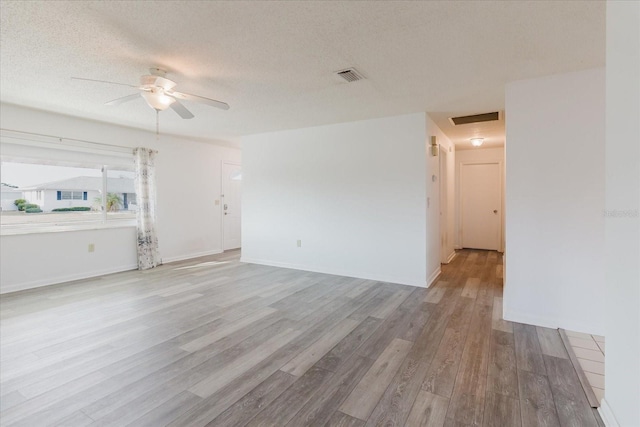 unfurnished room with a ceiling fan, light wood finished floors, a textured ceiling, and visible vents