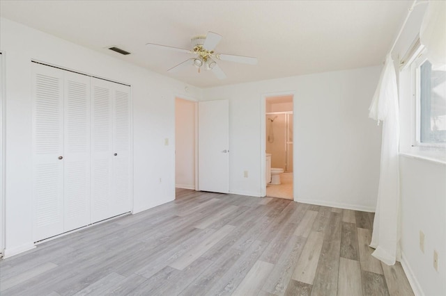 unfurnished bedroom featuring connected bathroom, ceiling fan, light wood-type flooring, visible vents, and a closet