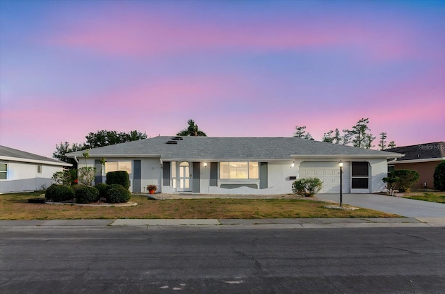 ranch-style house with an attached garage, driveway, stucco siding, and a front yard