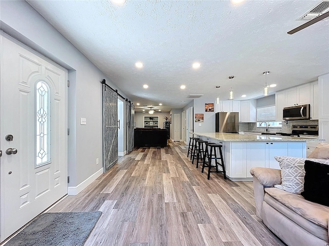 6811 S Himes Ave, Tampa, FL 33611 - entrance foyer with a barn door, a textured ceiling, light wood-style flooring, recessed lighting, and baseboards