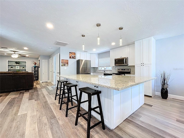 6811 S Himes Ave, Tampa, FL 33611 - kitchen featuring appliances with stainless steel finishes, light wood-style floors, baseboards, white cabinetry, and a textured ceiling