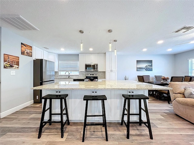 6811 S Himes Ave, Tampa, FL 33611 - kitchen featuring appliances with stainless steel finishes, a sink, white cabinetry, open floor plan, and a textured ceiling