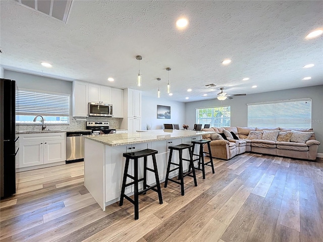 6811 S Himes Ave, Tampa, FL 33611 - kitchen with appliances with stainless steel finishes, a textured ceiling, light wood finished floors, a sink, and open floor plan