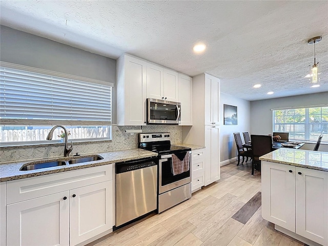 6811 S Himes Ave, Tampa, FL 33611 - kitchen with stainless steel appliances, a sink, white cabinets, light wood-type flooring, and decorative backsplash