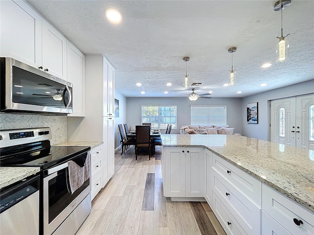 6811 S Himes Ave, Tampa, FL 33611 - kitchen featuring stainless steel appliances, a ceiling fan, white cabinets, light wood-style flooring, and a textured ceiling