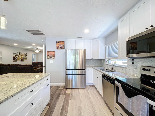 6811 S Himes Ave, Tampa, FL 33611 - kitchen with stainless steel appliances, a sink, light wood-style flooring, light stone counters, and tasteful backsplash