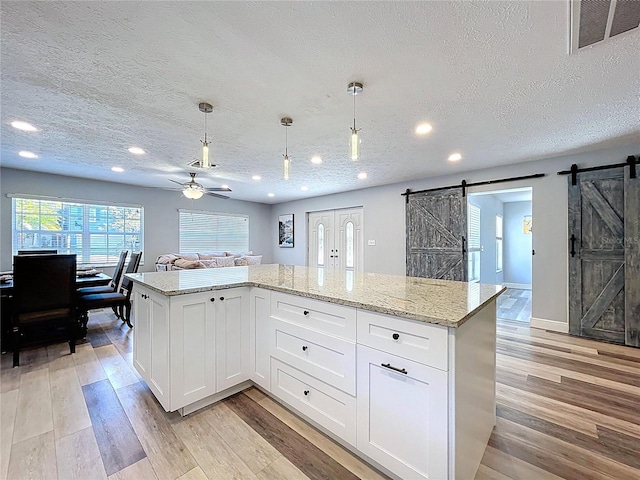 6811 S Himes Ave, Tampa, FL 33611 - kitchen with a barn door, a textured ceiling, a ceiling fan, light wood-type flooring, and recessed lighting