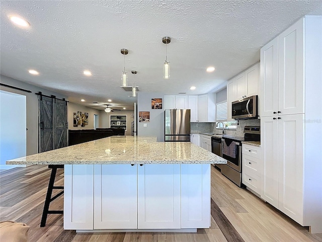 6811 S Himes Ave, Tampa, FL 33611 - kitchen featuring appliances with stainless steel finishes, a barn door, a kitchen island, ceiling fan, and a sink