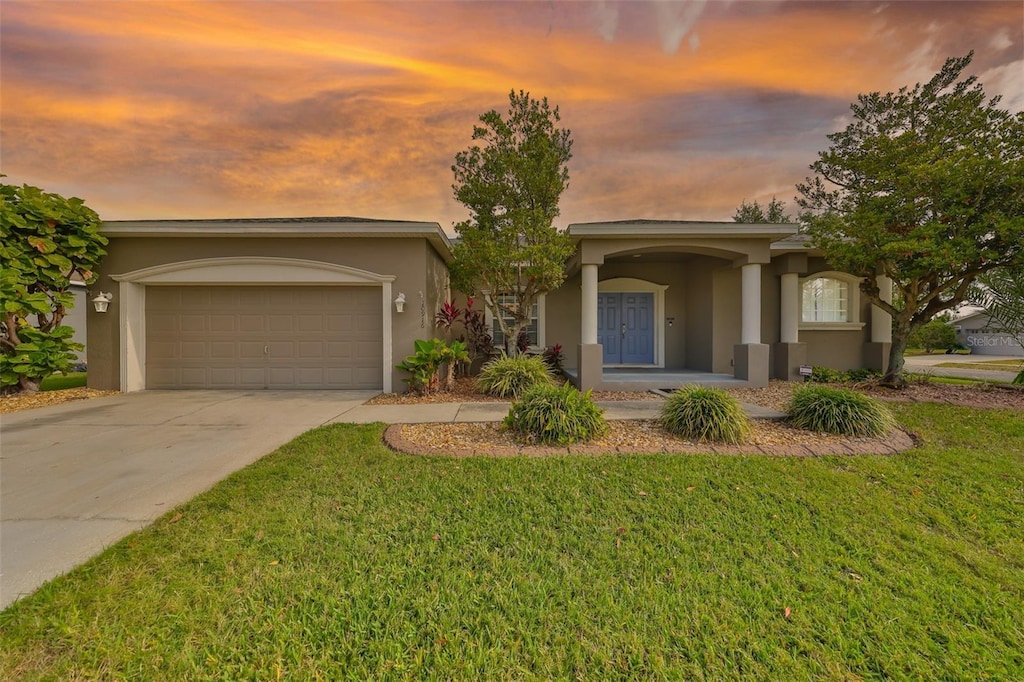 view of front of property featuring stucco siding, a front lawn, driveway, and a garage