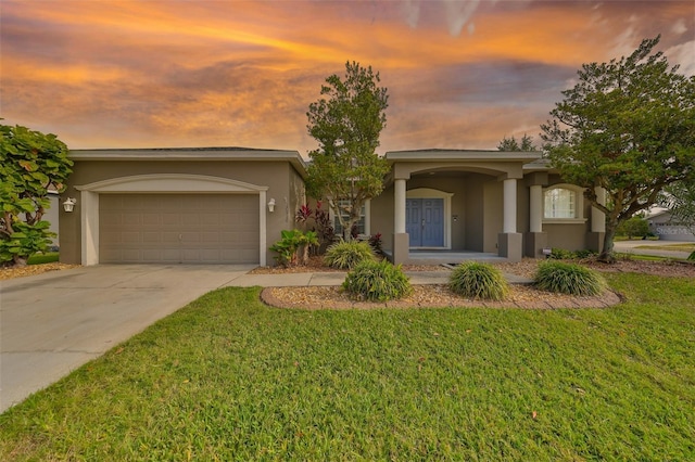 view of front of property featuring stucco siding, a front lawn, driveway, and a garage