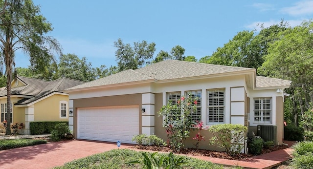 15324 Sherwood Forest Dr, Tampa, FL 33647 - view of front of home with decorative driveway, stucco siding, an attached garage, a shingled roof, and central AC