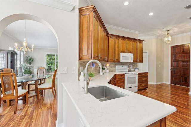 15324 Sherwood Forest Dr, Tampa, FL 33647 - kitchen featuring white appliances, a sink, a chandelier, light wood-style floors, and arched walkways