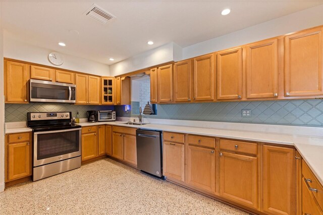 kitchen with stainless steel appliances, light countertops, visible vents, a sink, and tasteful backsplash