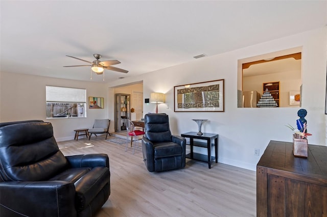 living area with baseboards, a ceiling fan, light wood-style floors, and visible vents