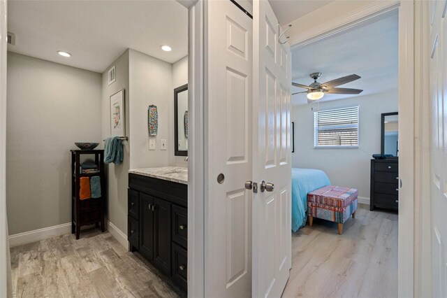 hallway with light wood-type flooring, visible vents, and baseboards