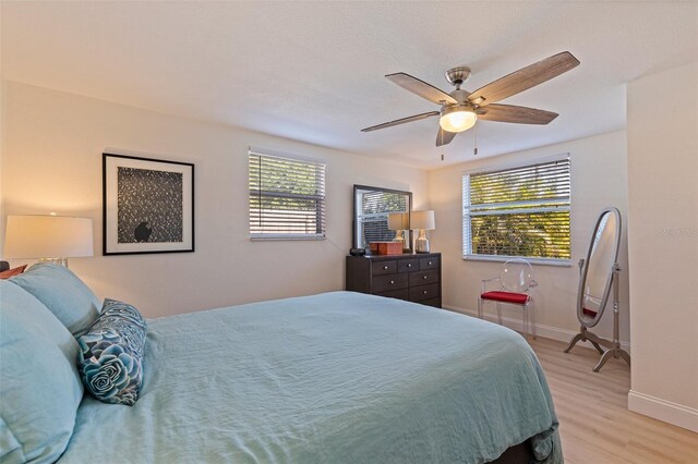 bedroom featuring light wood-type flooring, baseboards, and ceiling fan