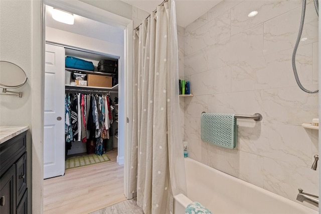 full bathroom with shower / bath combo, wood finished floors, vanity, and a walk in closet