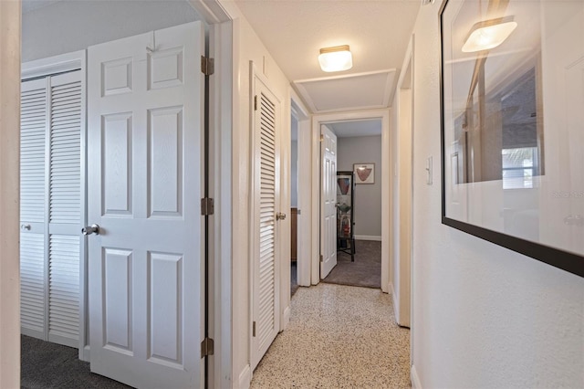 corridor featuring baseboards and speckled floor