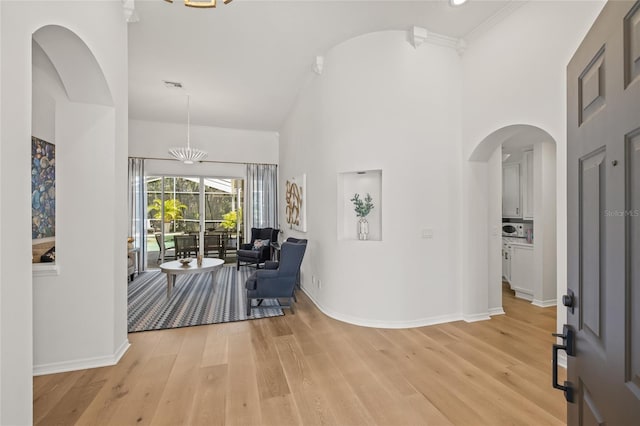 foyer entrance with baseboards, arched walkways, visible vents, and light wood-style flooring